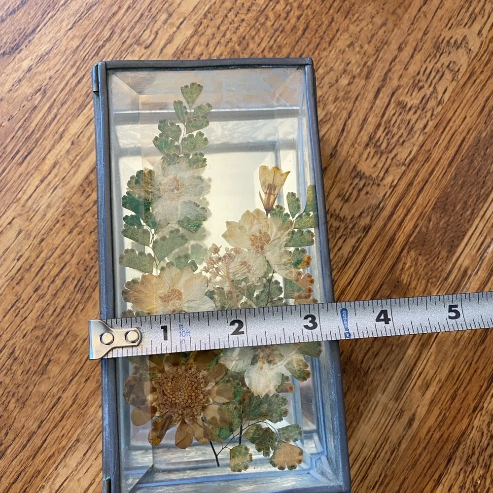 Small, heavy glass box with pressed flowers on top and mirrored bottom